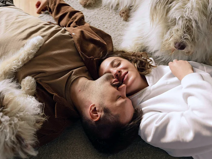 @lang('Casal relaxado deitado no chão entre cães de estimação, transmitindo tranquilidade e alívio após consolidar os seus créditos.')